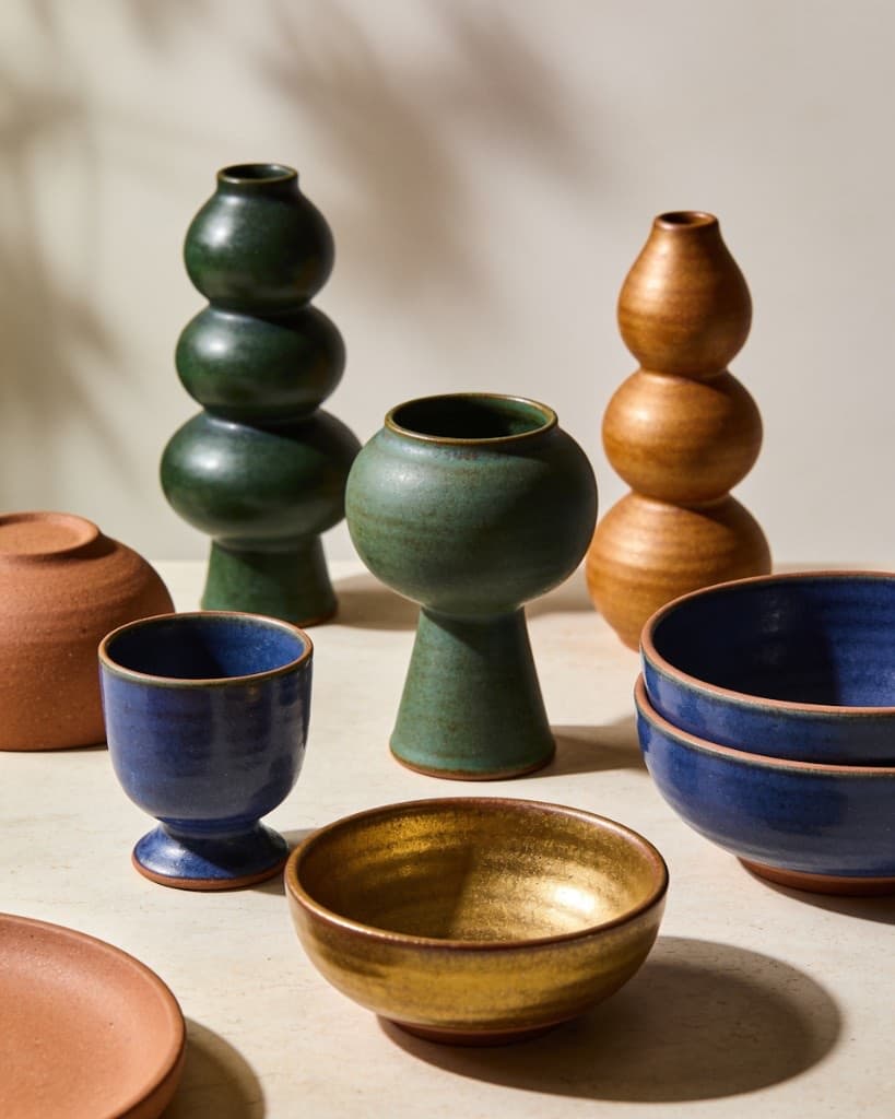 Curated ceramic vessels in earth and jewel tones on a light studio surface